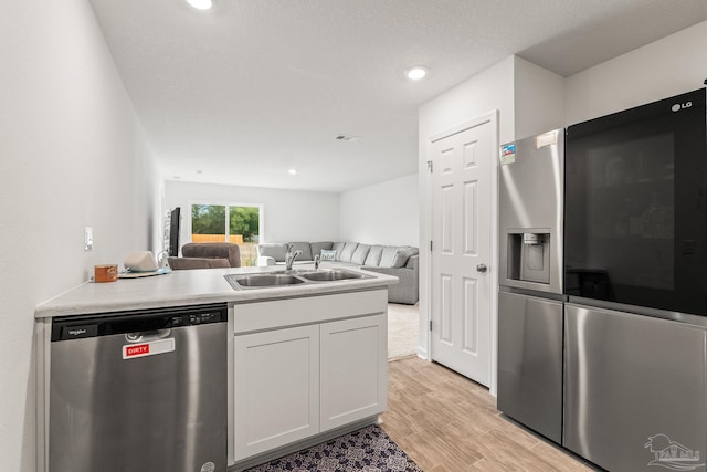 kitchen with stainless steel appliances, white cabinetry, sink, and light wood-type flooring