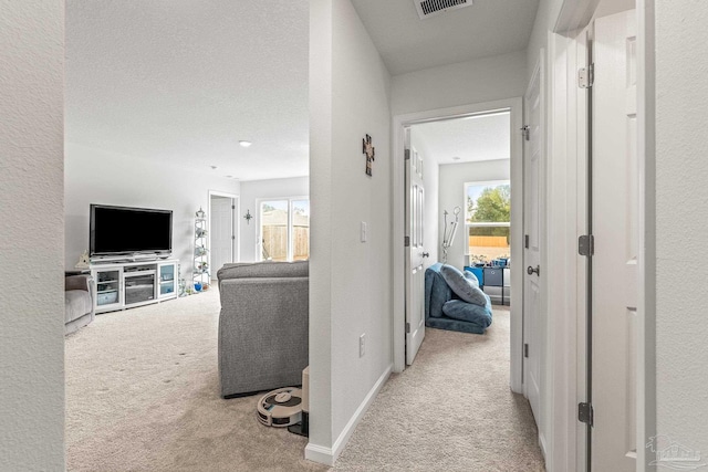 hall featuring light carpet and a textured ceiling