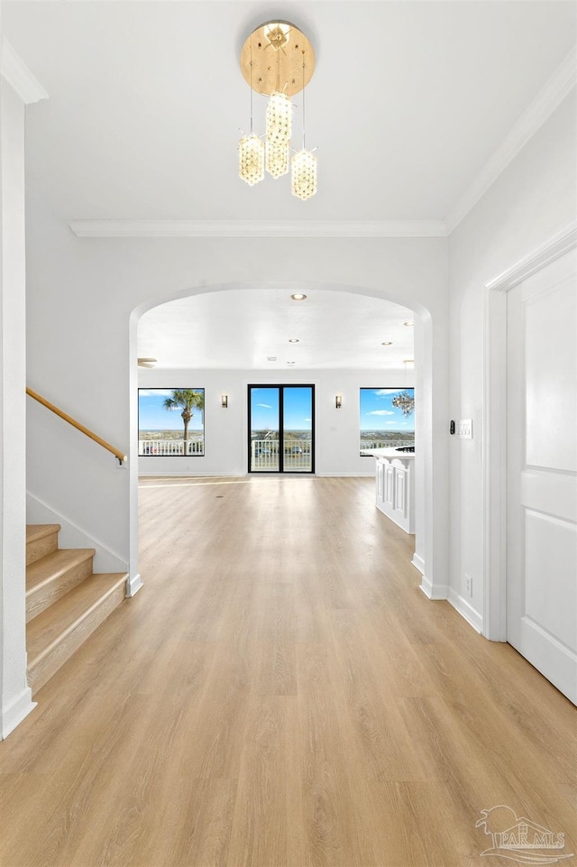 unfurnished living room featuring a notable chandelier, light hardwood / wood-style flooring, and ornamental molding