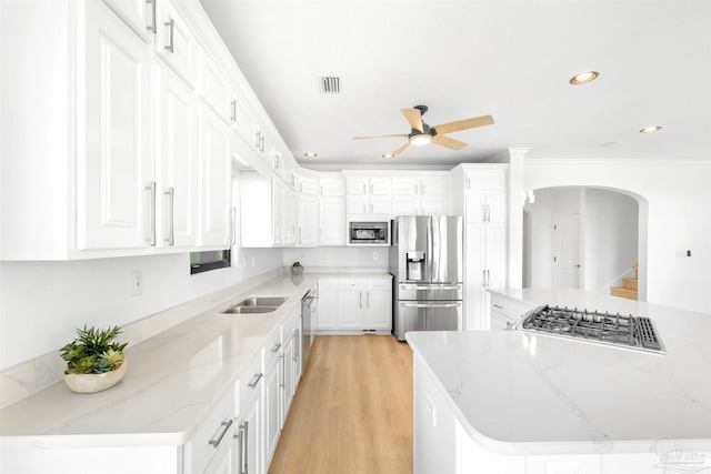 kitchen with appliances with stainless steel finishes, light stone countertops, light hardwood / wood-style floors, and white cabinets