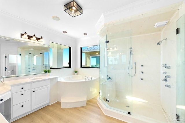 bathroom featuring plus walk in shower, ornamental molding, hardwood / wood-style floors, and vanity