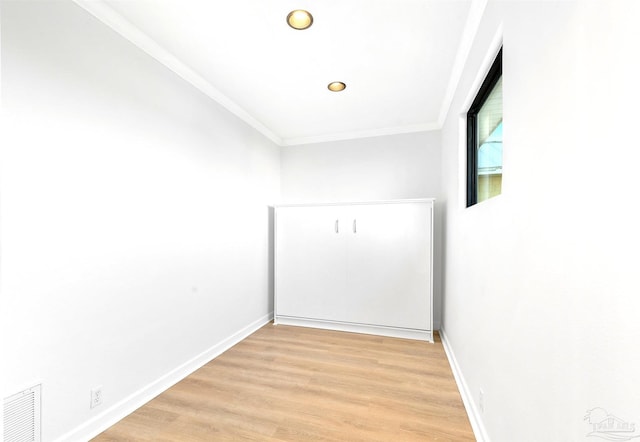 spare room featuring crown molding and light hardwood / wood-style flooring