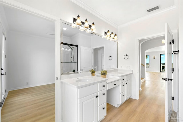 bathroom with walk in shower, ornamental molding, wood-type flooring, and vanity