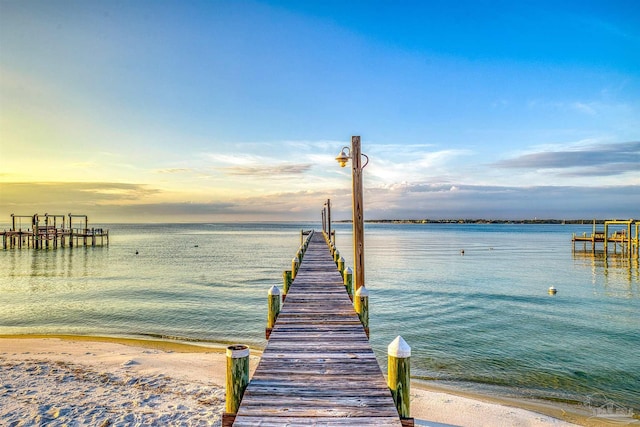 view of dock featuring a beach view and a water view