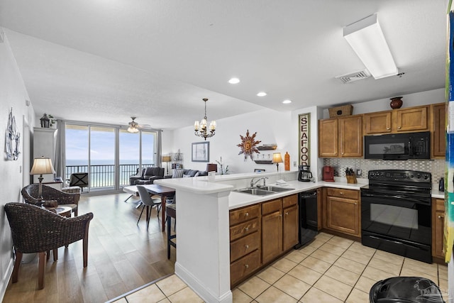 850 Ft Pickens Rd Unit 1230, Pensacola Beach, FL 32561 - kitchen featuring black appliances, brown cabinets, open floor plan, a peninsula, and floor to ceiling windows
