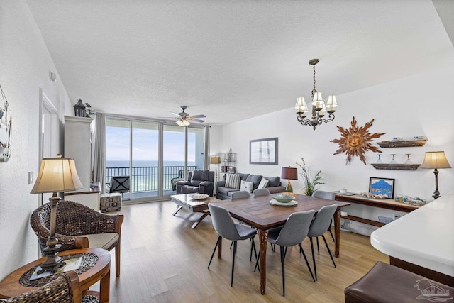 850 Ft Pickens Rd Unit 1230, Pensacola Beach, FL 32561 - dining space featuring a wall of windows, light wood-style flooring, a textured ceiling, a chandelier, and a ceiling fan