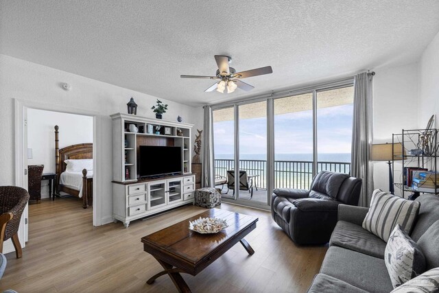 850 Ft Pickens Rd Unit 1230, Pensacola Beach, FL 32561 - living room featuring a ceiling fan, light wood-style floors, expansive windows, and a textured ceiling