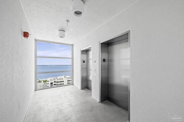 850 Ft Pickens Rd Unit 1230, Pensacola Beach, FL 32561 - hall with elevator, a textured wall, a water view, a textured ceiling, and floor to ceiling windows