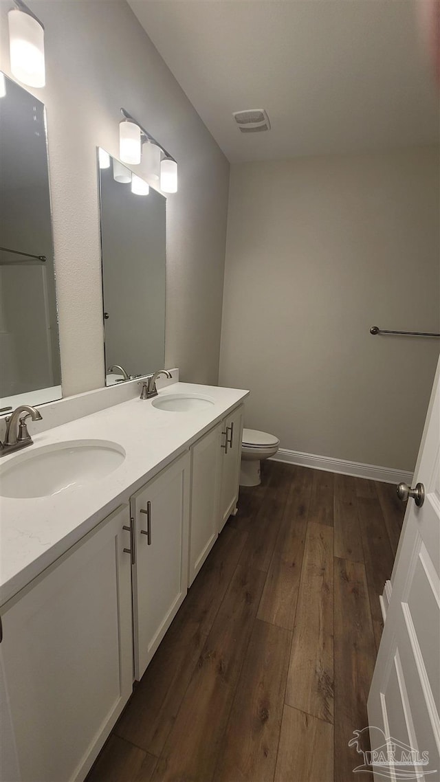 bathroom with hardwood / wood-style floors, toilet, visible vents, and a sink