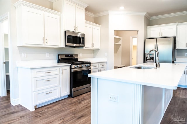 kitchen featuring a center island with sink, ornamental molding, appliances with stainless steel finishes, wood finished floors, and a sink