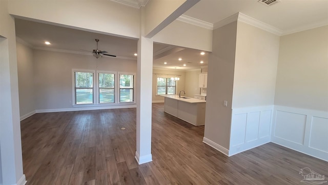 unfurnished living room with dark wood-style flooring, crown molding, and a sink