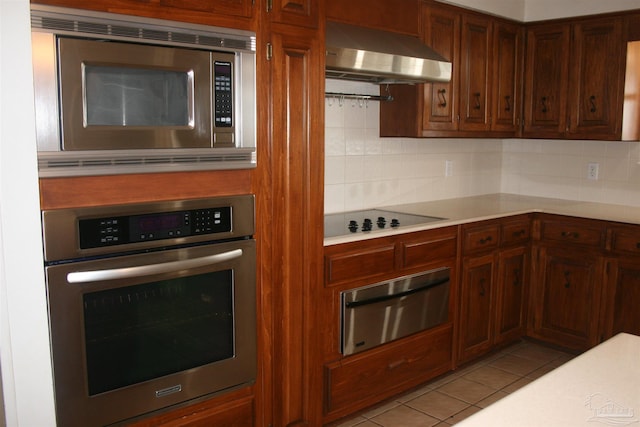 kitchen with tasteful backsplash, appliances with stainless steel finishes, light tile patterned floors, and range hood