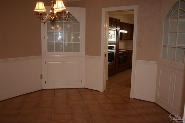 unfurnished dining area with an inviting chandelier and tile patterned floors