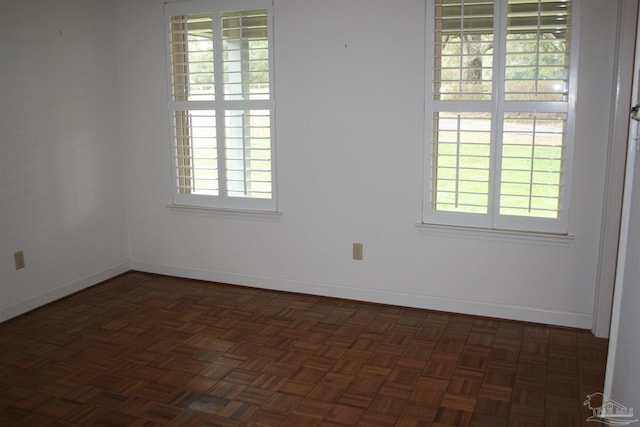 unfurnished room featuring dark parquet floors and a wealth of natural light