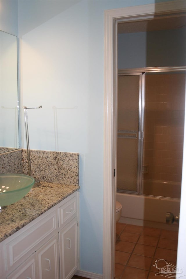 full bathroom featuring tile patterned flooring, vanity, combined bath / shower with glass door, and toilet