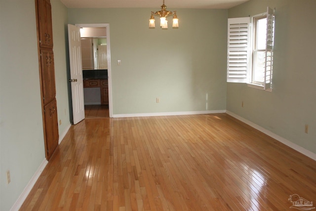 spare room with a notable chandelier and light hardwood / wood-style flooring