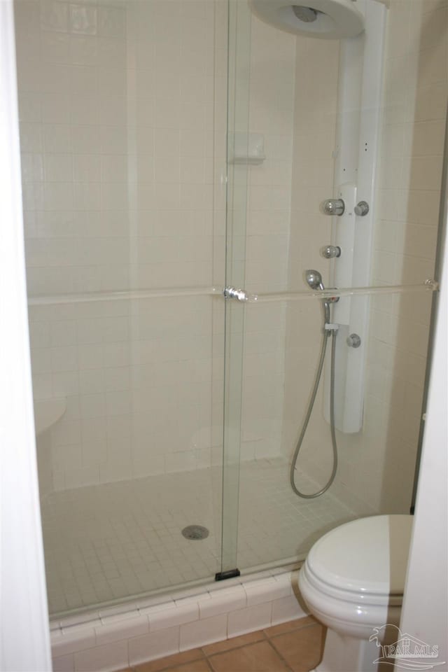 bathroom featuring tile patterned flooring, an enclosed shower, and toilet