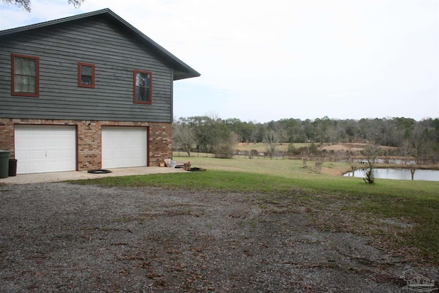 view of home's exterior with a yard, a garage, and a water view