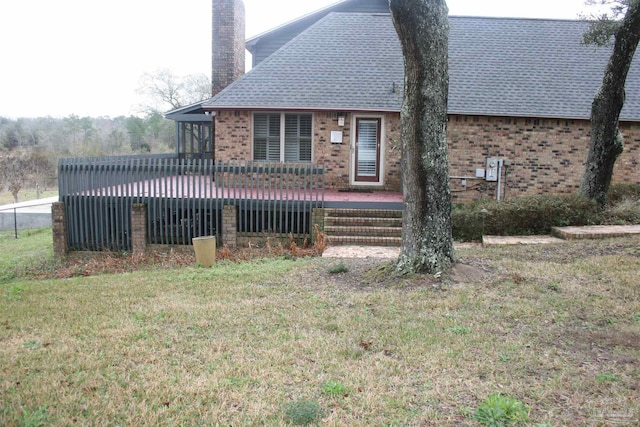 rear view of house featuring a wooden deck and a lawn