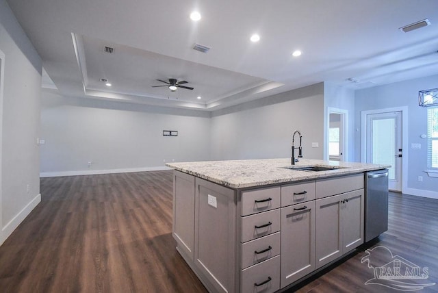 kitchen with ceiling fan, dishwasher, sink, dark wood-type flooring, and a center island with sink