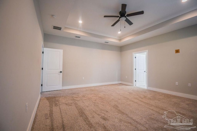 carpeted empty room featuring a tray ceiling and ceiling fan