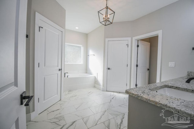 bathroom with a notable chandelier, a tub, and vanity