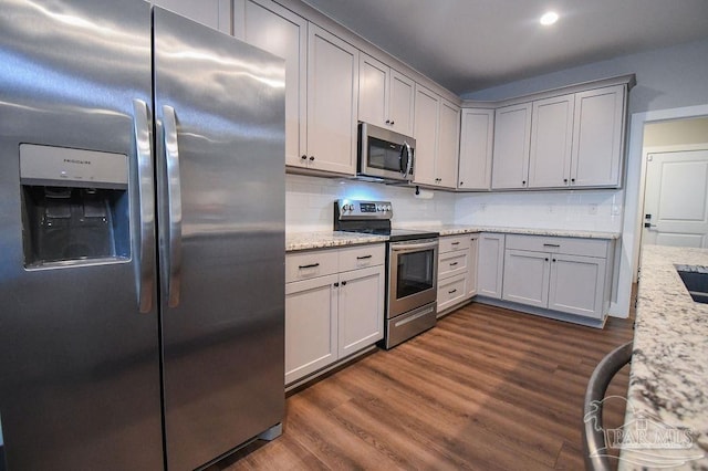 kitchen with dark hardwood / wood-style floors, gray cabinets, decorative backsplash, light stone countertops, and appliances with stainless steel finishes