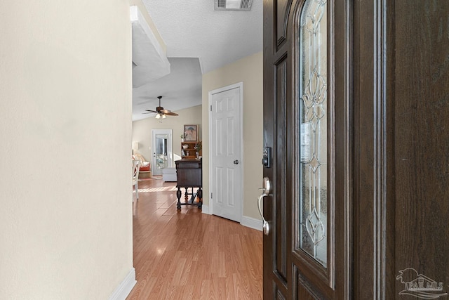 entryway with ceiling fan, vaulted ceiling, a textured ceiling, and light hardwood / wood-style floors