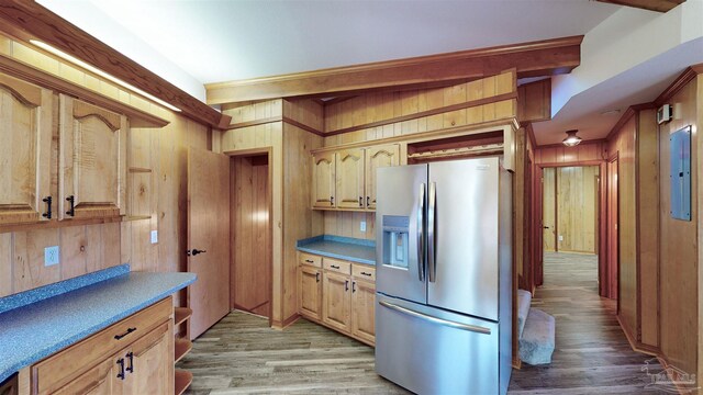 kitchen featuring stainless steel fridge with ice dispenser, hardwood / wood-style flooring, electric panel, wooden walls, and ornamental molding