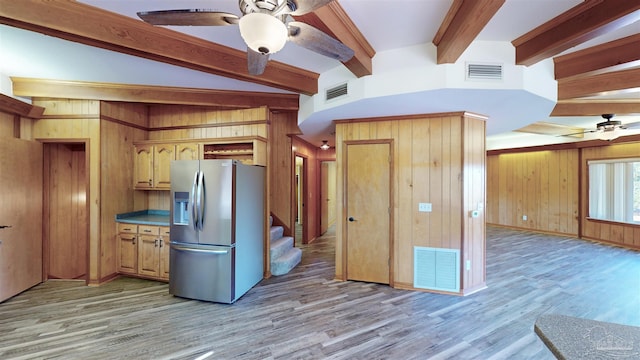 kitchen with ceiling fan, vaulted ceiling with beams, stainless steel refrigerator with ice dispenser, light hardwood / wood-style floors, and wooden walls