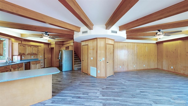 kitchen with appliances with stainless steel finishes, dark hardwood / wood-style floors, beam ceiling, and wood walls