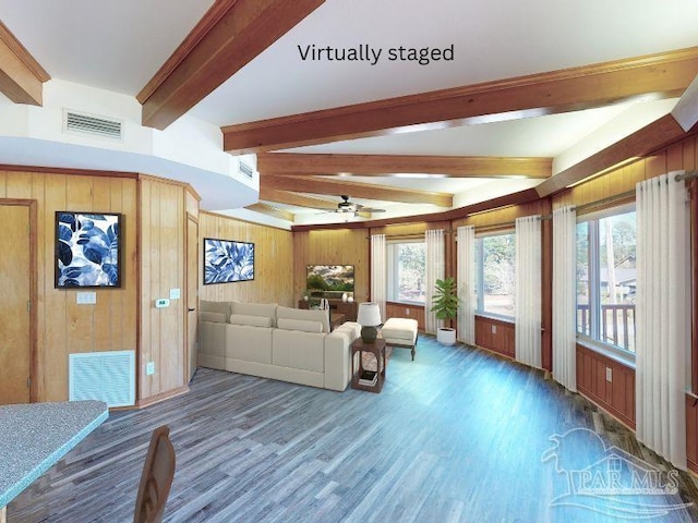 unfurnished living room with wood walls, ceiling fan, beam ceiling, and hardwood / wood-style floors