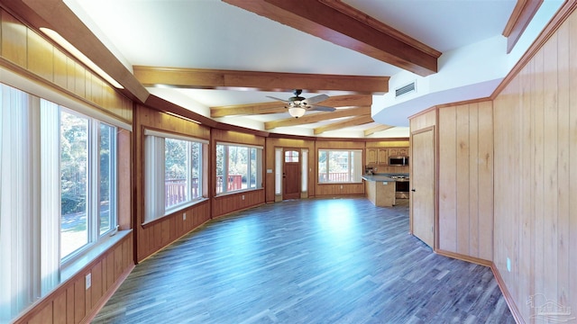 unfurnished living room featuring wooden walls, dark hardwood / wood-style flooring, ceiling fan, and lofted ceiling with beams