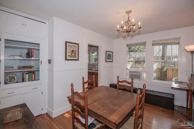 dining room featuring a textured ceiling, a chandelier, and wood-type flooring