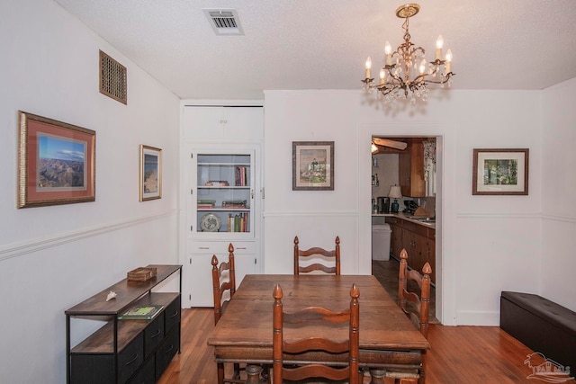 dining area featuring a textured ceiling, a notable chandelier, and hardwood / wood-style floors