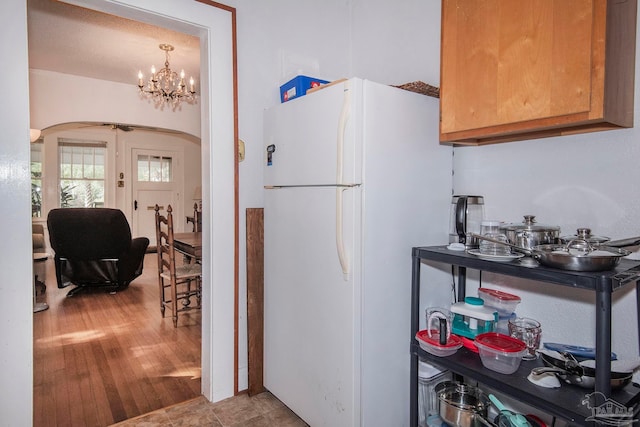 kitchen with a notable chandelier, light hardwood / wood-style flooring, decorative light fixtures, and white fridge