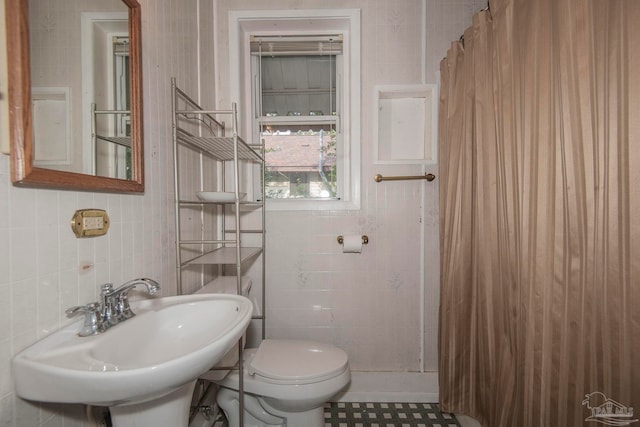 bathroom with tile patterned floors, tile walls, and toilet