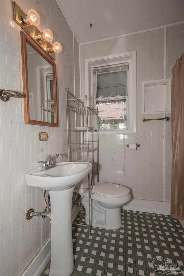 bathroom with tile patterned flooring, tile walls, and toilet