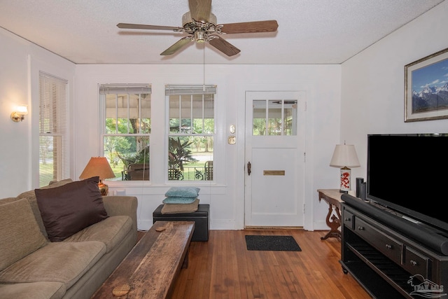 living room featuring ceiling fan, a textured ceiling, and light hardwood / wood-style floors