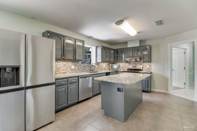 kitchen with stainless steel appliances, backsplash, visible vents, a sink, and glass insert cabinets
