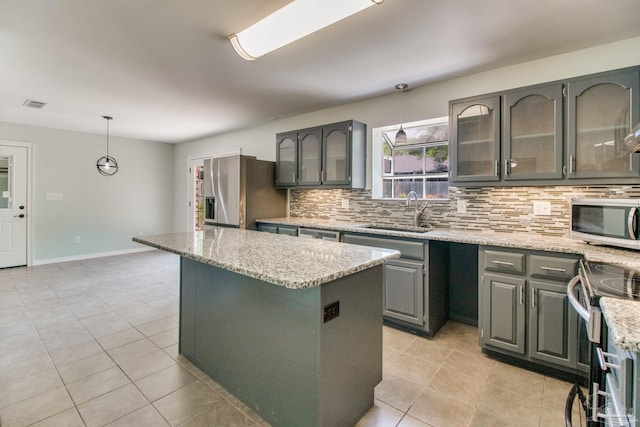 kitchen with stainless steel appliances, a center island, a sink, light tile patterned flooring, and tasteful backsplash