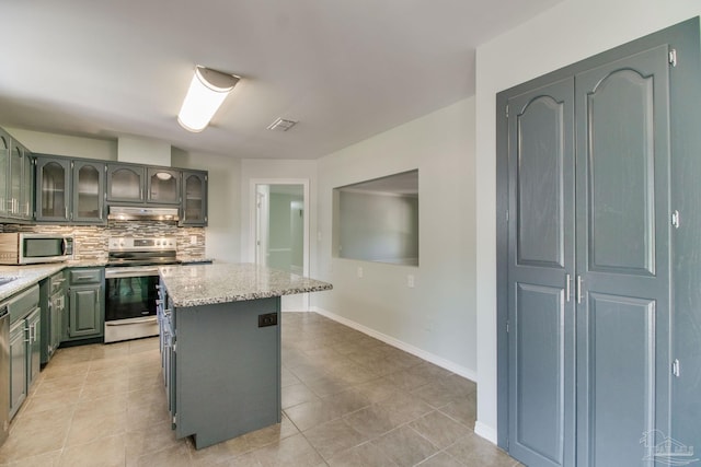 kitchen with tasteful backsplash, appliances with stainless steel finishes, under cabinet range hood, light stone countertops, and visible vents