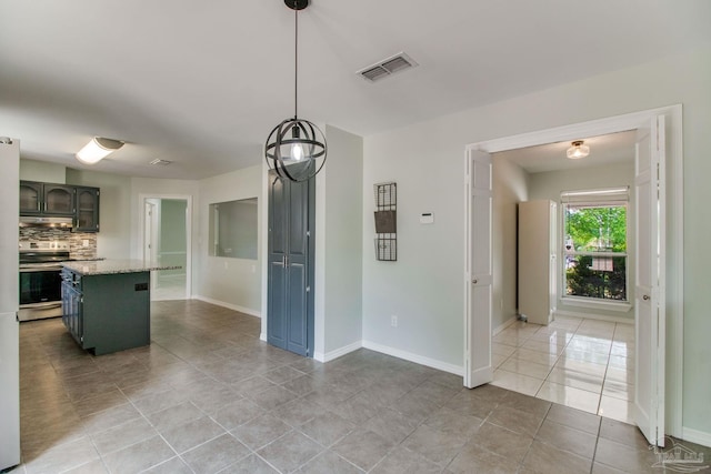 kitchen with tasteful backsplash, light tile patterned flooring, stainless steel range, under cabinet range hood, and visible vents