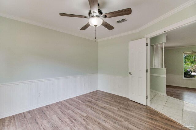 unfurnished room with crown molding, wood finished floors, ceiling fan, a wainscoted wall, and visible vents