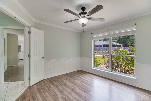 unfurnished room featuring wood finished floors, ornamental molding, ceiling fan, and wainscoting
