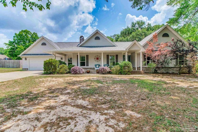 view of front of property featuring a porch, an attached garage, a chimney, and fence
