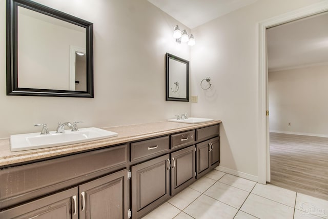 bathroom featuring baseboards, tile patterned flooring, a sink, and double vanity