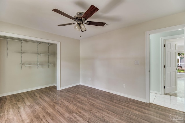 unfurnished bedroom featuring wood finished floors, a closet, a ceiling fan, and baseboards