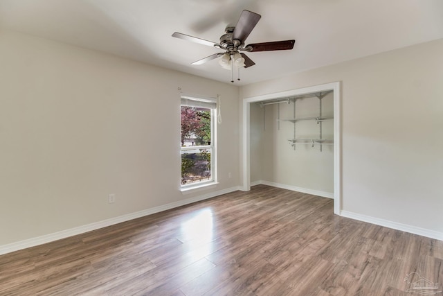 unfurnished bedroom featuring baseboards, a ceiling fan, wood finished floors, and a closet