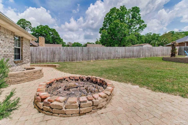 view of yard with a fire pit, a fenced backyard, and a patio